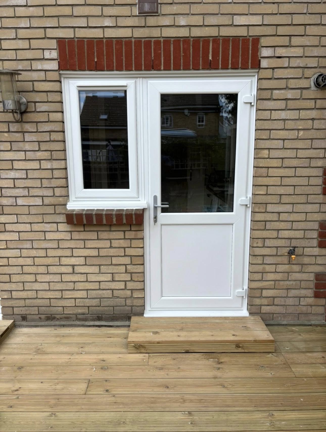 White uPVC back door with side window on a brick wall