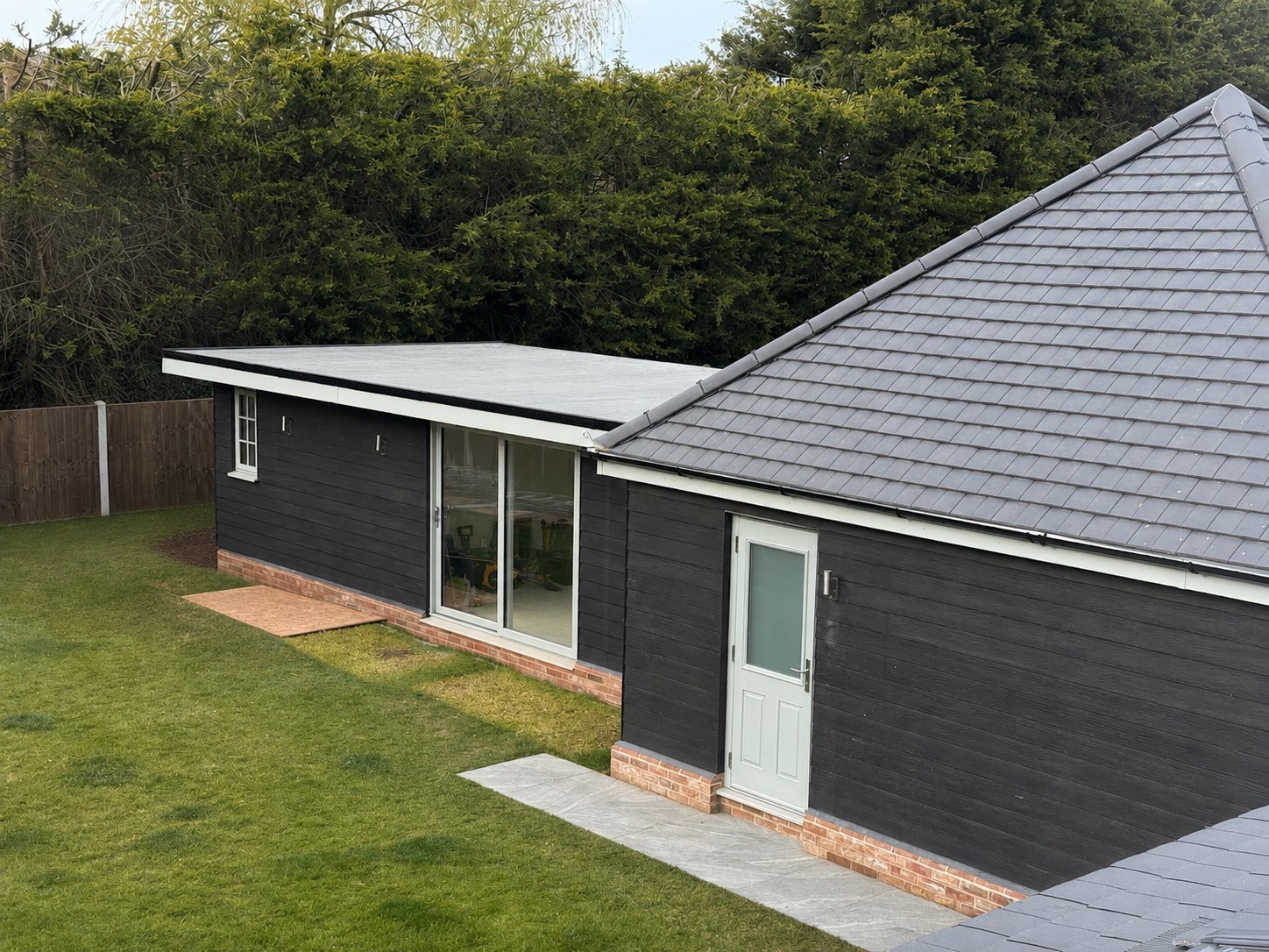 A modern garden room with cladding and bi-fold doors set on a lawn