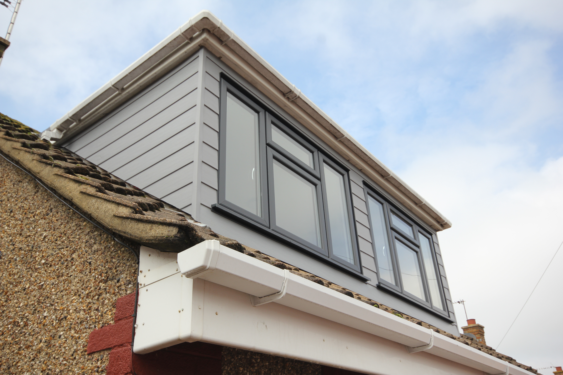 A loft dormer conversion with grey cladding and large anthracite-framed windows