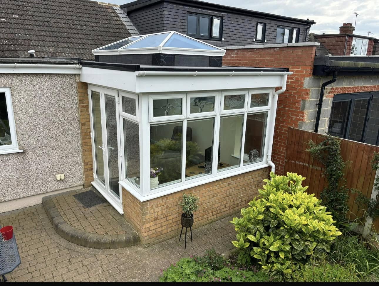 White orangery with glazed roof lantern overlooking a garden