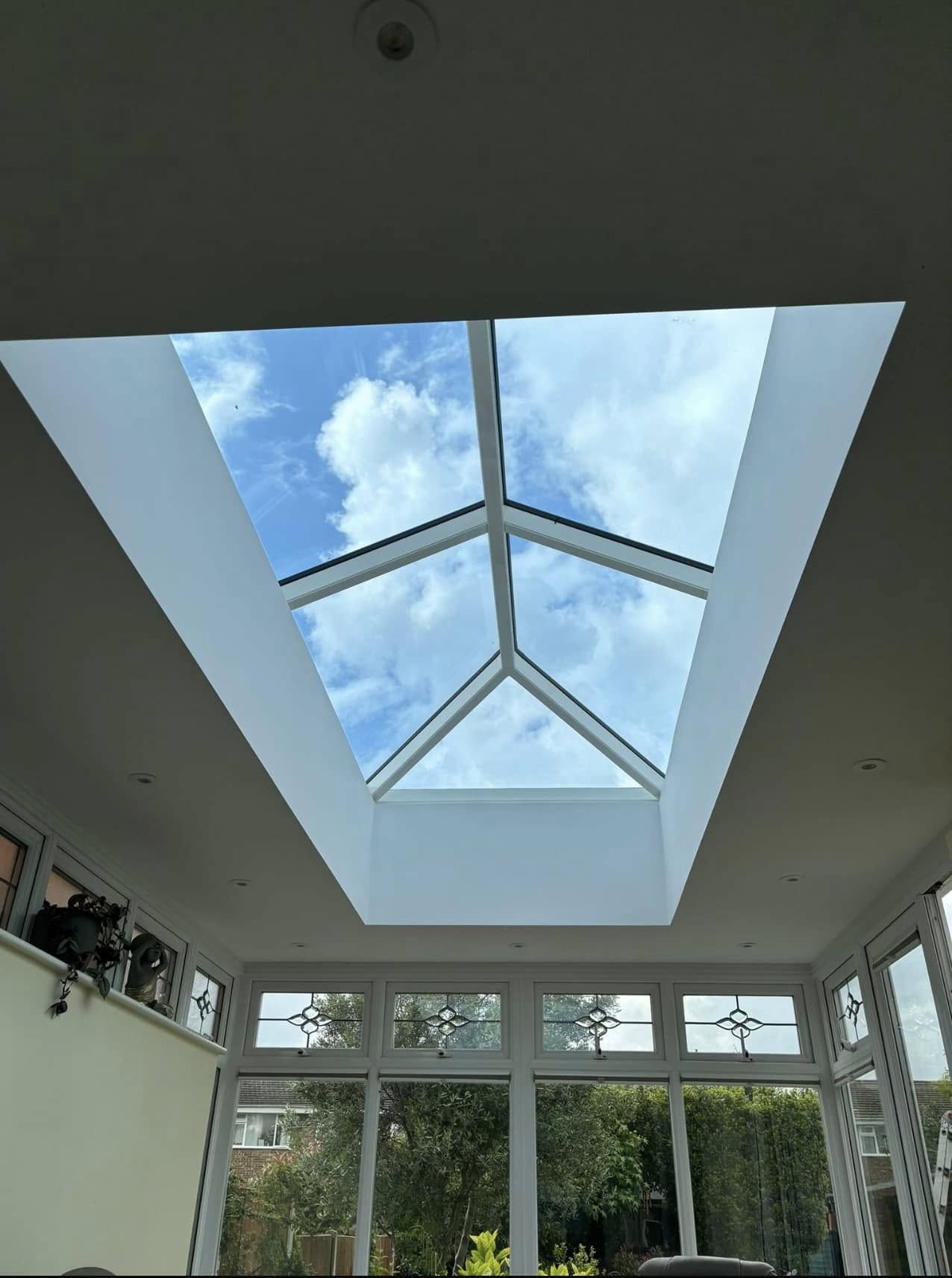 Interior view looking up through an orangery roof lantern at blue sky