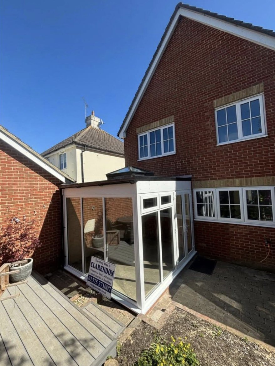White orangery built onto raised decking on a sunny day