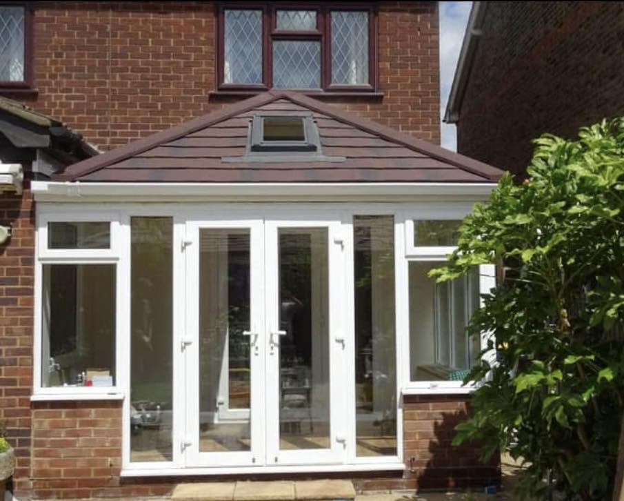 Brown tiled-roof orangery with French doors on a sunny day