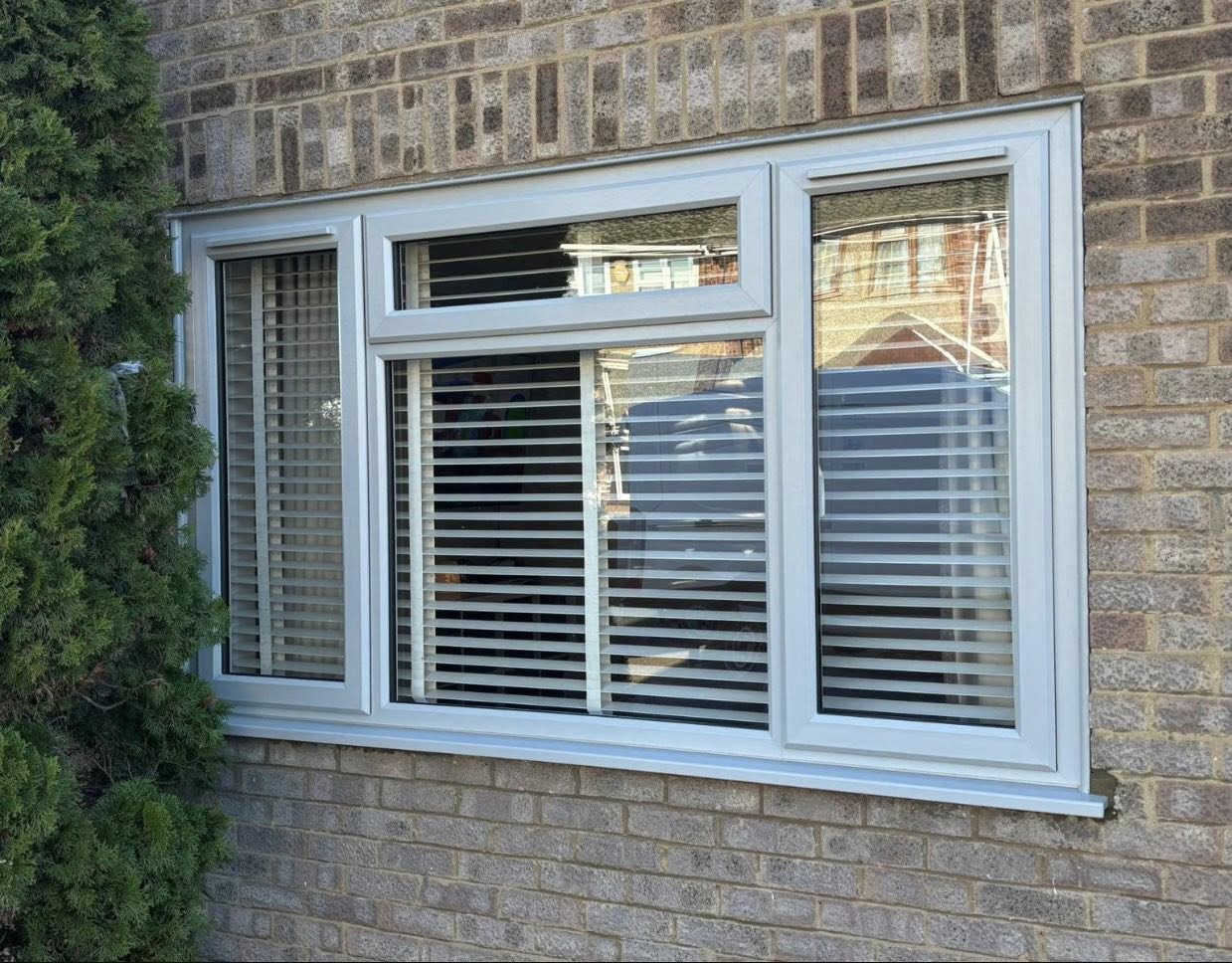 Light grey uPVC casement window with top openers on a brick home