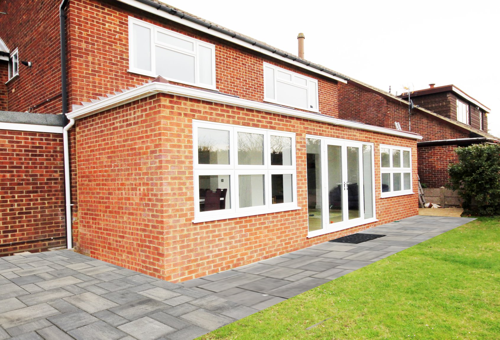 Red brick rear extension with white uPVC casement windows and French doors